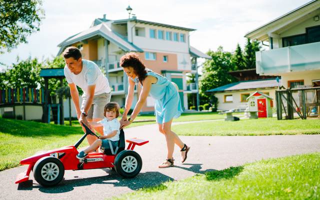 Eltern schieben Kind in Gokart an