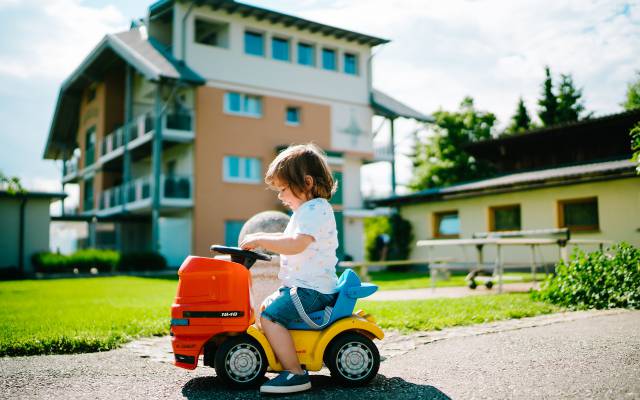 Kind auf Rutschauto vorm Karglhof