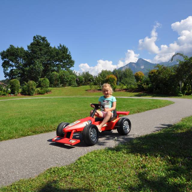 Mädchen sitzt auf dem Rennauto für Kinder