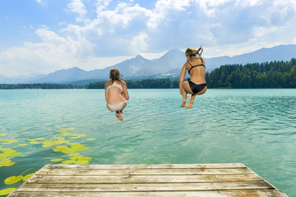 Zwei Frauen hüpfen in den See vom Steg aus