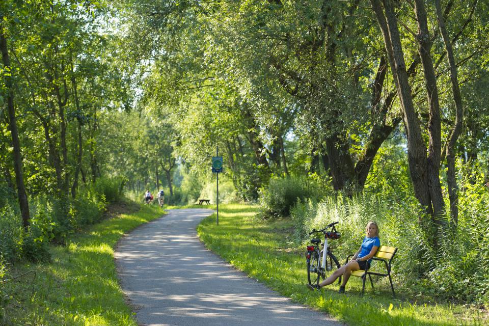 Frau macht Pause vom Radfahren an einer Bank